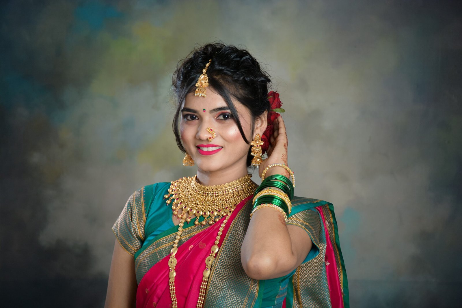 Smiling Indian woman in a saree adorned with gold jewelry, exuding traditional elegance.