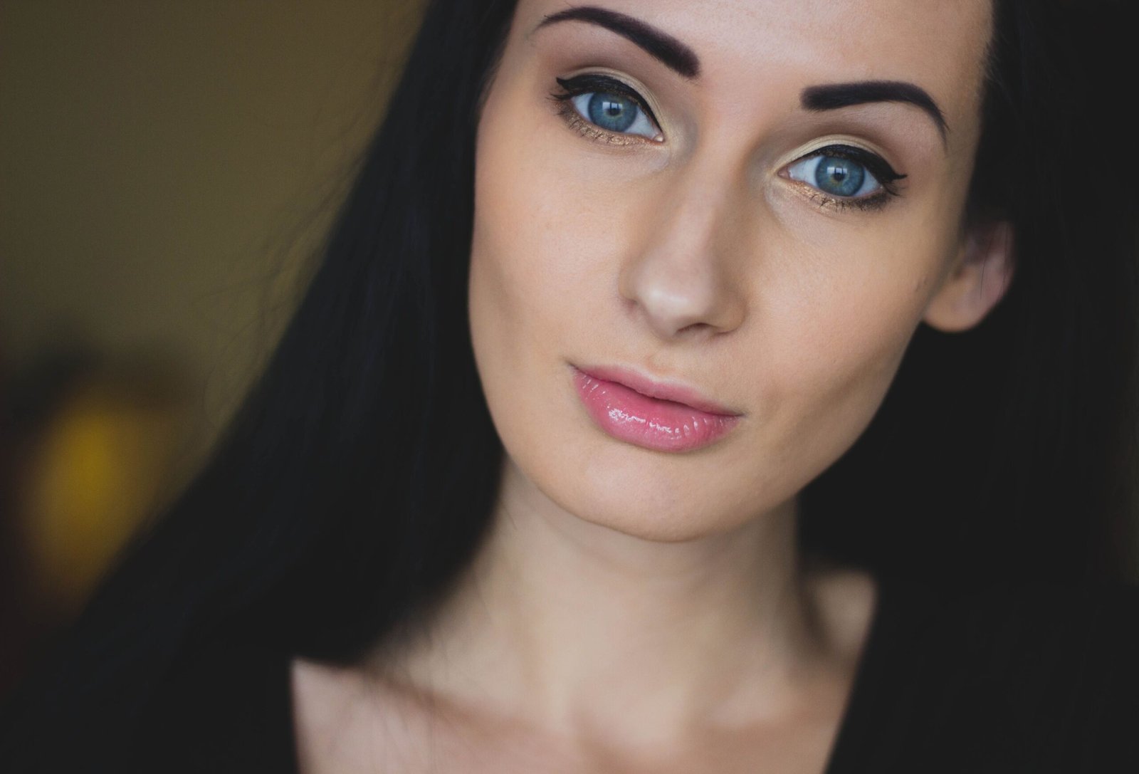 A striking close-up portrait of a young woman with striking blue eyes and black hair.